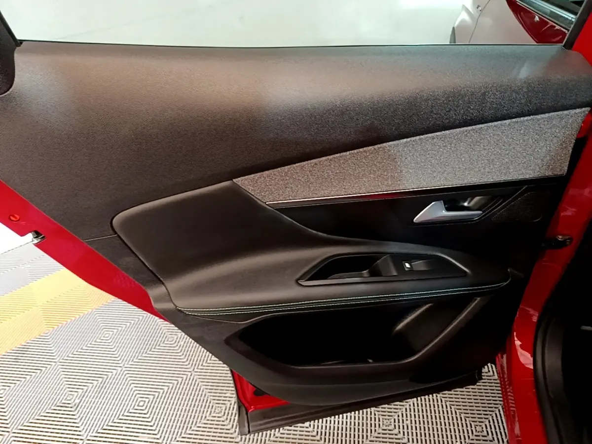 Vue intérieure de la porte arrière gauche rouge du Peugeot 3008 1.6 Hybrid 225 Allure Pack avec garniture noire et grise.