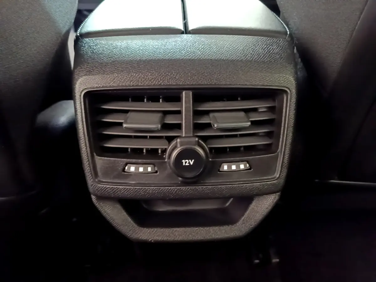 Gros plan sur la sortie d’air arrière noire avec prise 12V et commandes de chauffage du Peugeot 3008 hybride rechargeable.