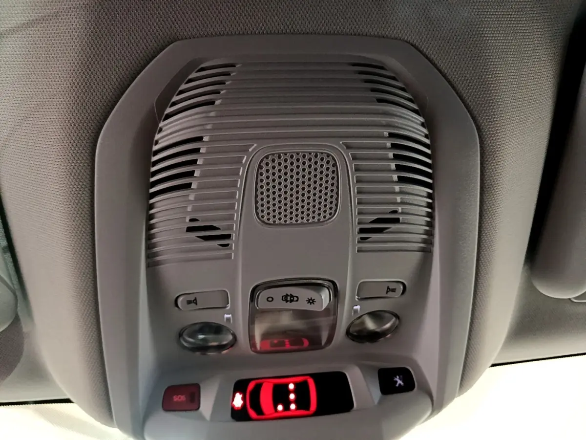 Vue en gros plan du plafonnier gris avec commandes lumineuses et affichage rouge du système d'alerte du Peugeot 3008 hybride.