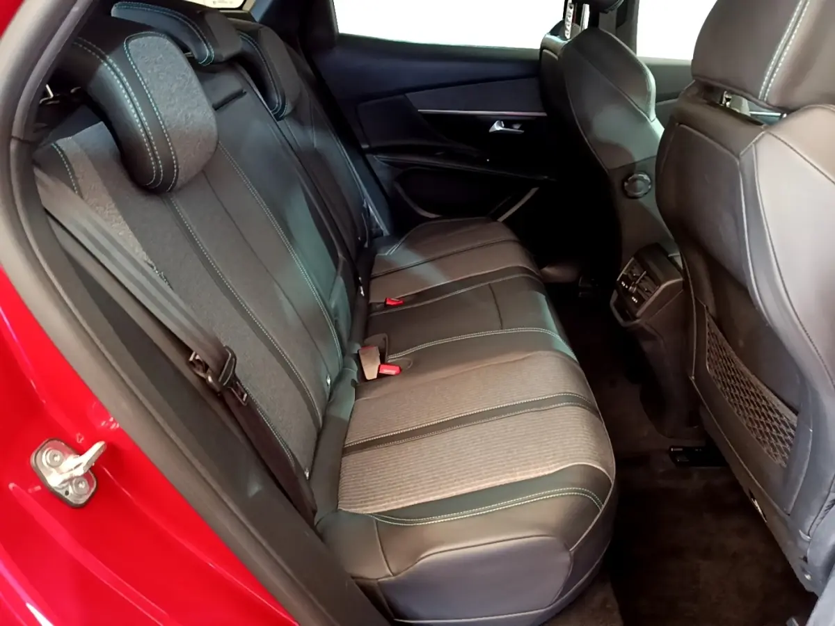 Vue intérieure côté arrière gauche du Peugeot 3008 hybride rechargeable 2021, sièges arrière en tissu et cuir noir avec surpiqûres vertes.