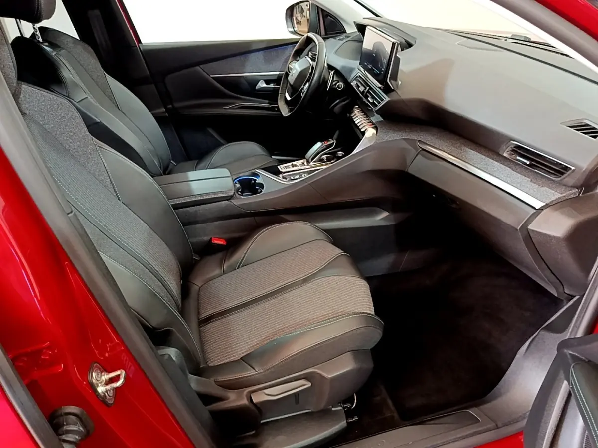 Vue intérieur côté passager avant du Peugeot 3008 hybride rechargeable 2021 avec sièges tissu et cuir noirs et tableau de bord moderne.