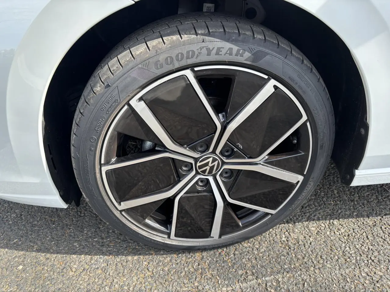 Gros plan sur la roue avant droite d’une Volkswagen Golf blanche 2024 avec jante noire et argentée distinctive.