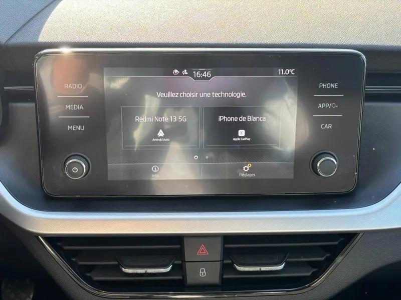 Écran tactile central du Skoda Kamiq 2023 avec interface multimédia et commandes autour, intérieur noir et argenté.