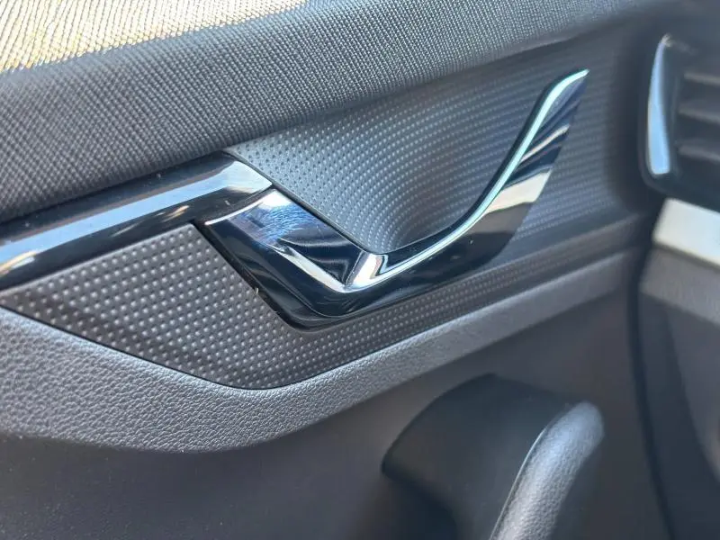 Poignée de porte intérieure noire brillante avec textures grises, détail du côté gauche d'une Skoda Kamiq 2023 Ambition.