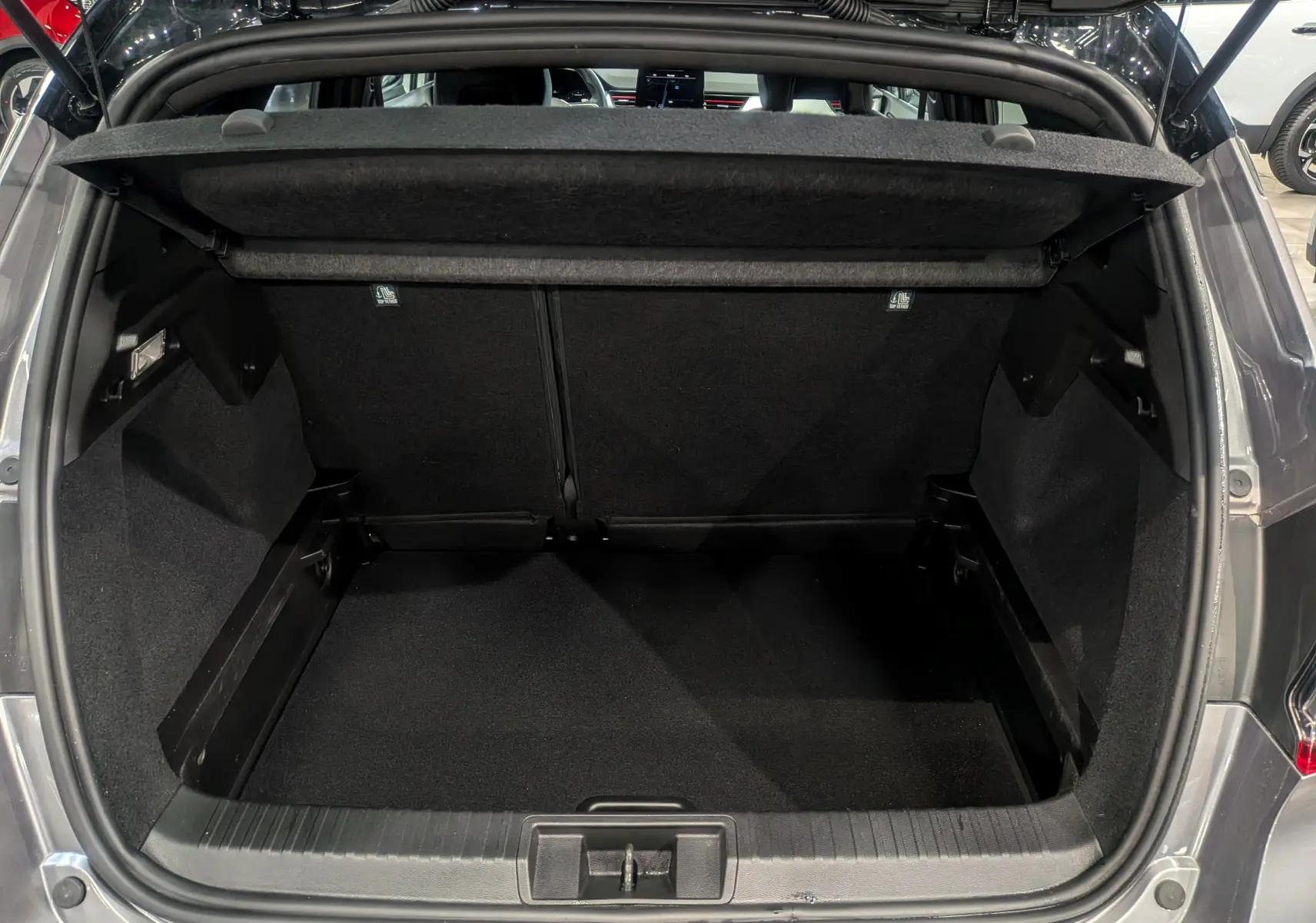 Coffre ouvert vu de l'arrière d'un Renault Captur TCe 160 gris Cassiopé avec toit noir, intérieur noir spacieux et propre.