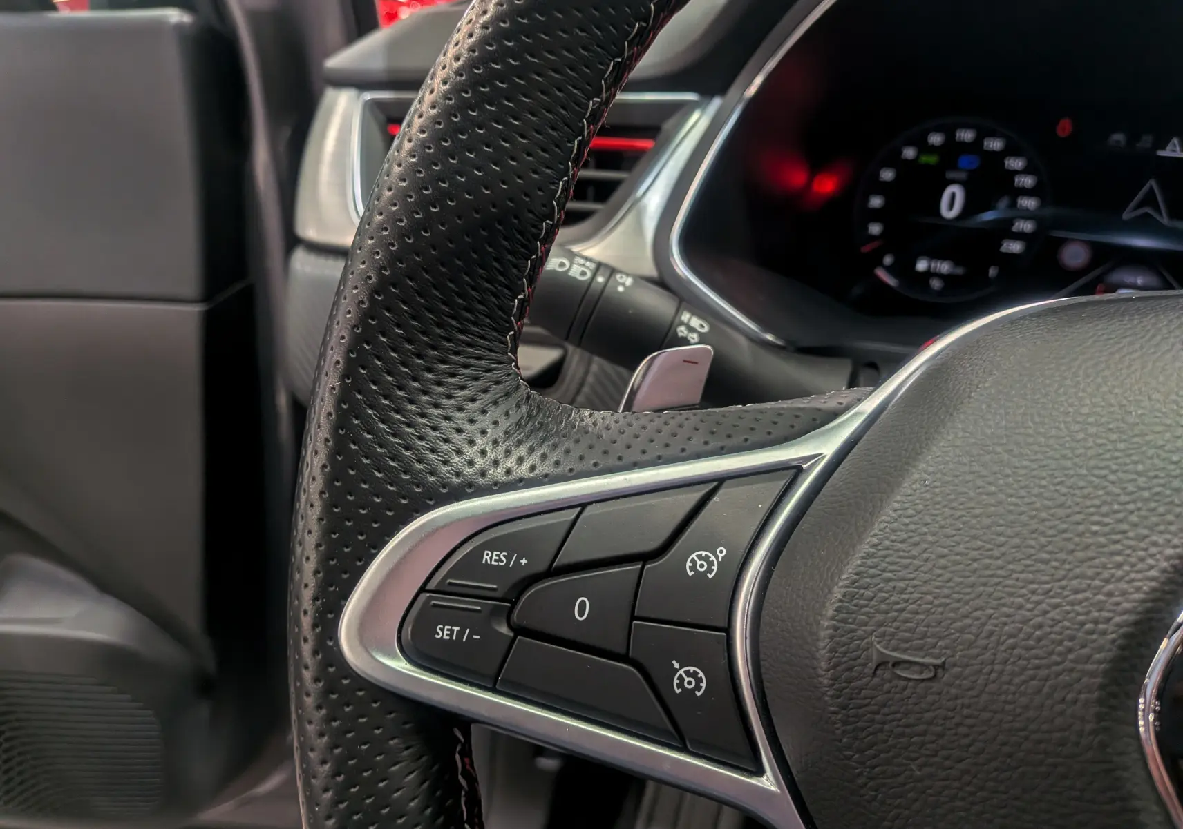 Gros plan sur le volant en cuir noir perforé du Renault Captur TCe 160 R.S. Line, avec commandes intégrées côté gauche.