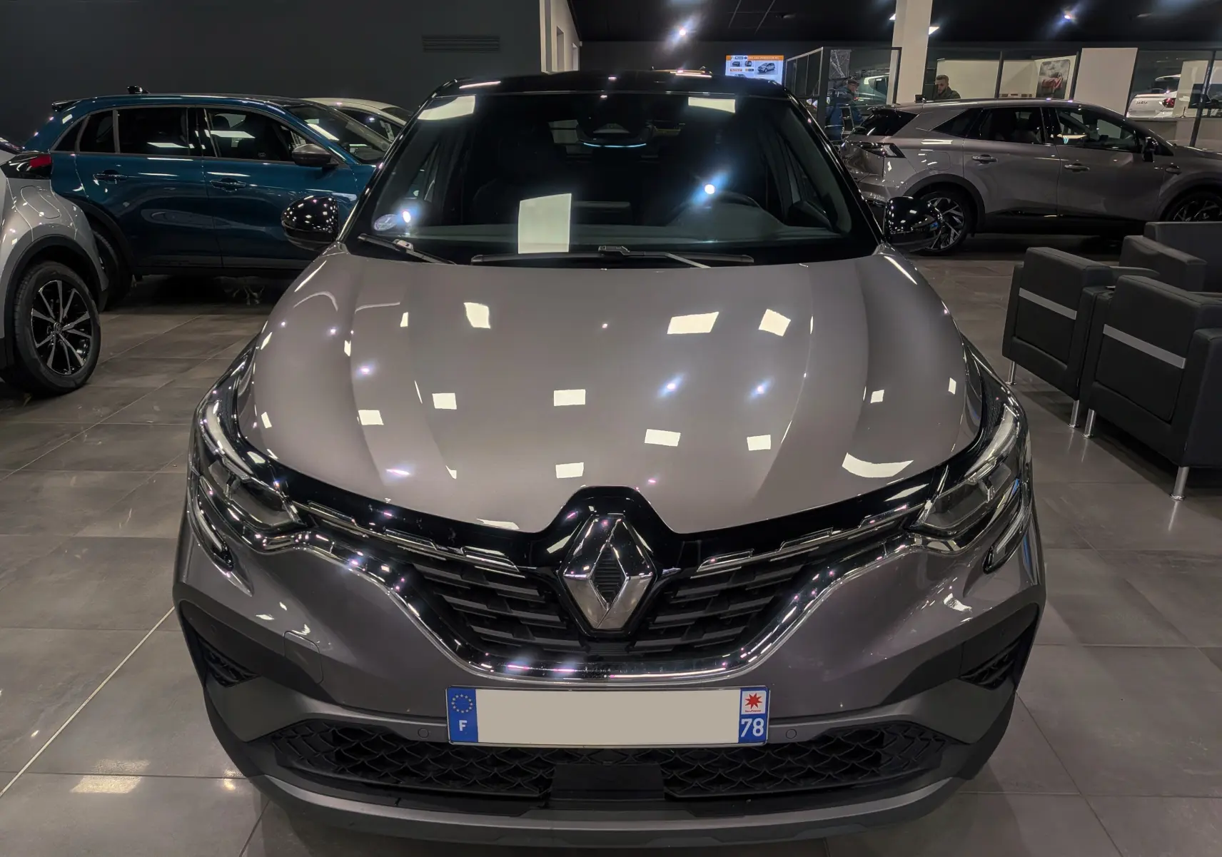 Vue frontale du Renault Captur TCe 160 R.S. Line gris Cassiopé avec toit noir dans un showroom éclairé.