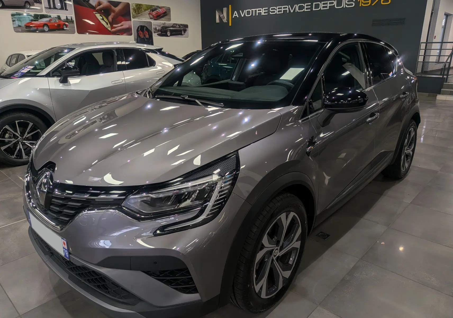 Vue 3/4 avant droit d'un Renault Captur TCe 160 R.S. Line gris Cassiopé avec toit noir en showroom.
