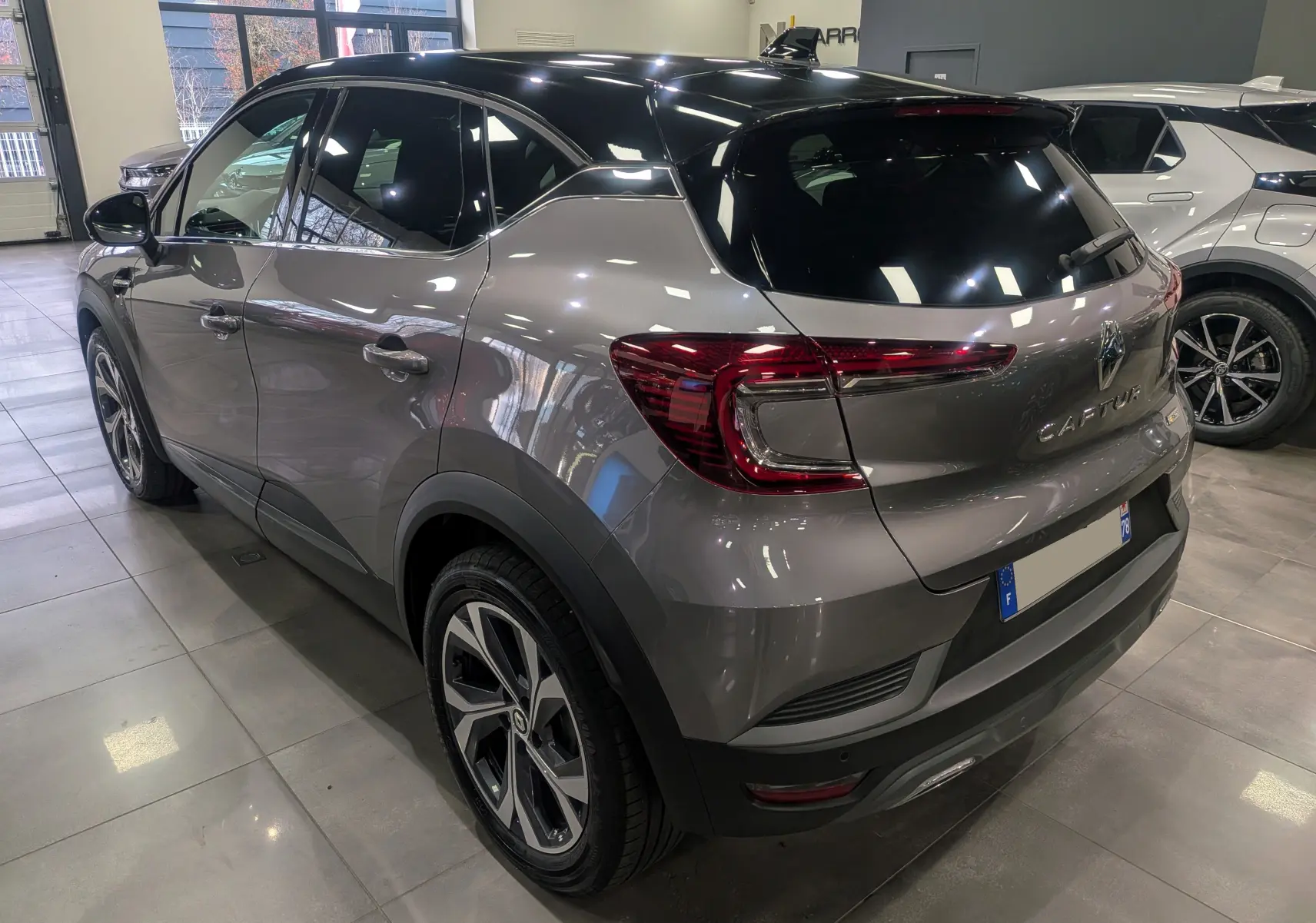 Vue 3/4 arrière droite du Renault Captur TCe 160 R.S. Line gris Cassiopé avec toit noir en showroom.