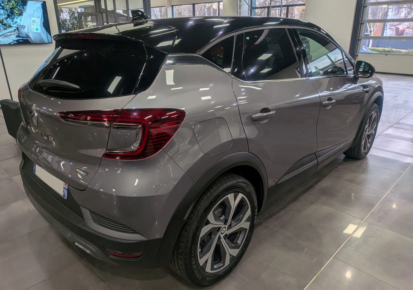 Vue 3/4 arrière droite du Renault Captur TCe 160 R.S. Line gris Cassiopé avec toit noir en showroom.