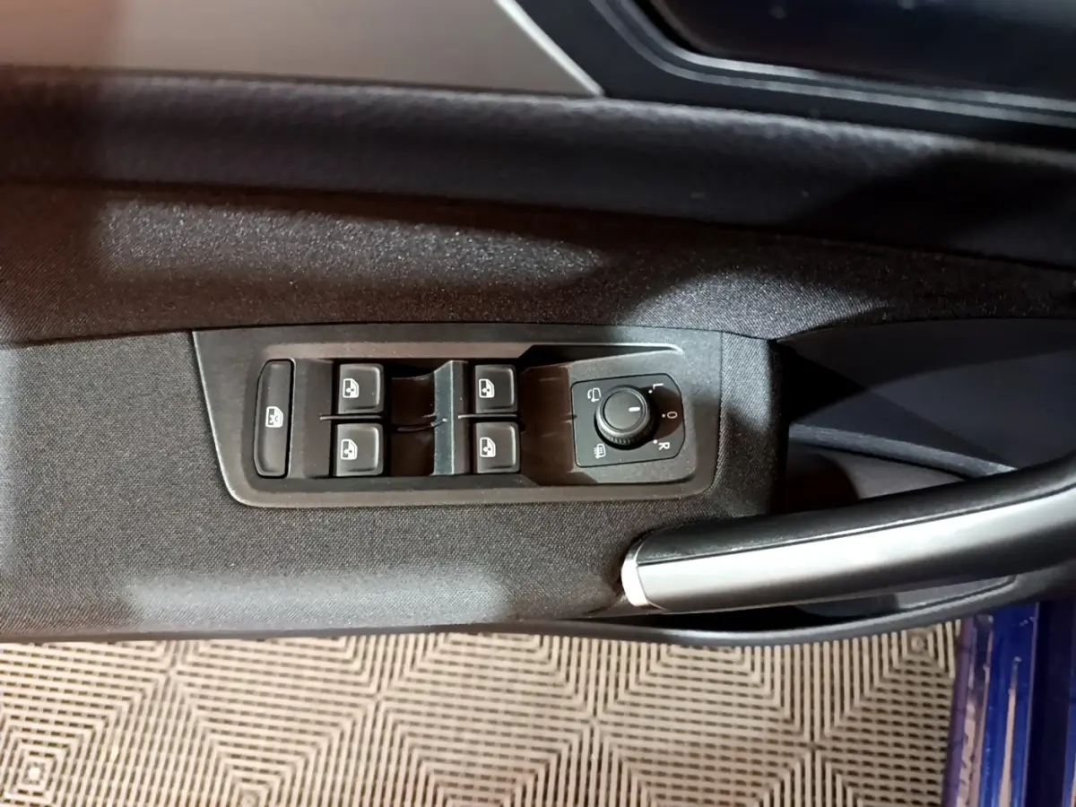 Vue rapprochée des commandes de lève-vitres et rétroviseurs côté conducteur du Volkswagen Touran bleu 2021.