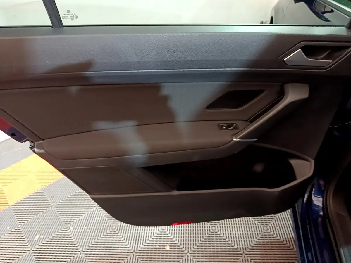 Porte intérieure côté gauche noire du Volkswagen Touran 1.5 TSI EVO DSG7 United bleu, avec poignée et commande de vitre.