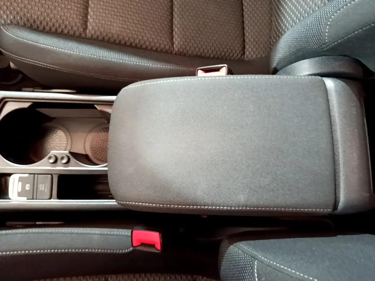 Vue plongeante sur l'accoudoir central noir et les sièges tissu gris du Volkswagen Touran 2021.