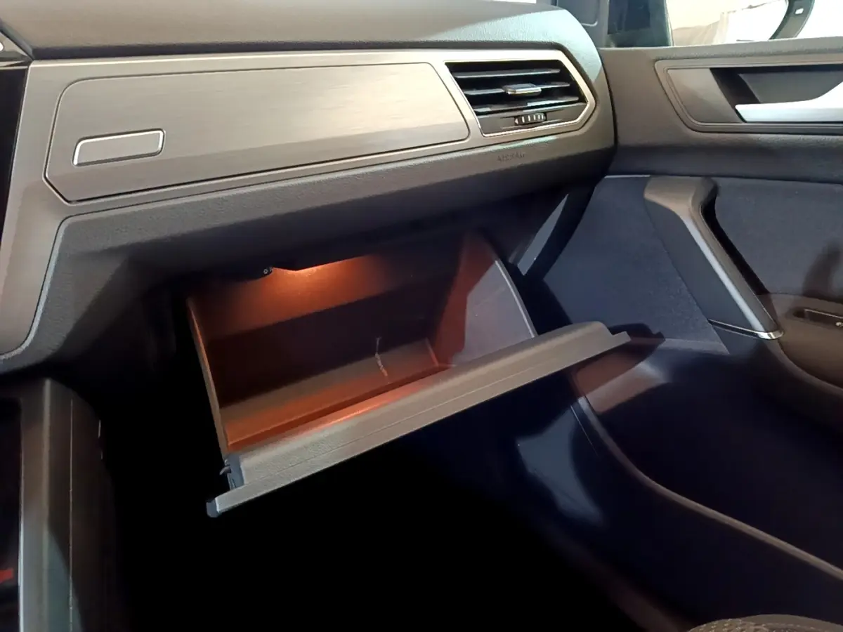 Intérieur du Volkswagen Touran 1.5 TSI EVO DSG7 United 2021, vue côté passager sur boîte à gants ouverte éclairée.
