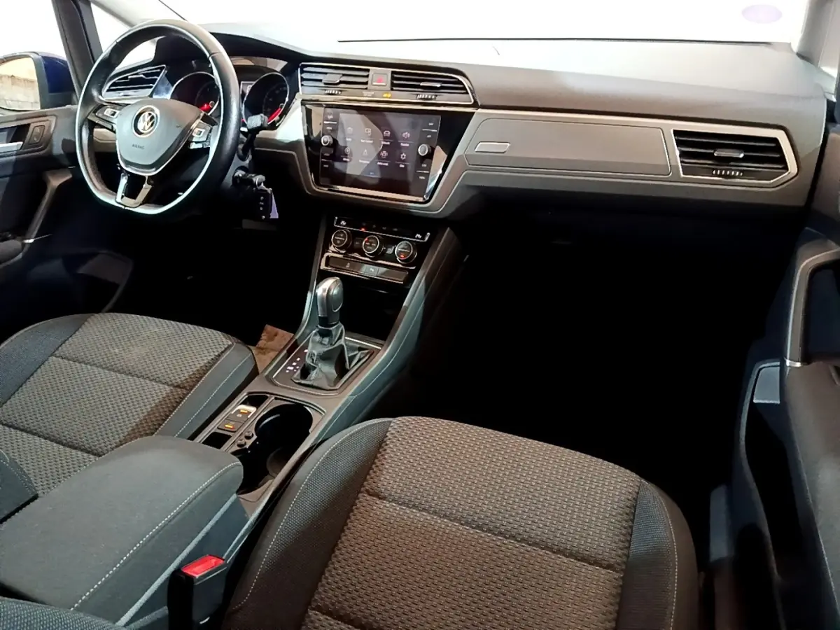 Intérieur avant du Volkswagen Touran 2021, vue côté conducteur, tableau de bord noir avec écran tactile central.