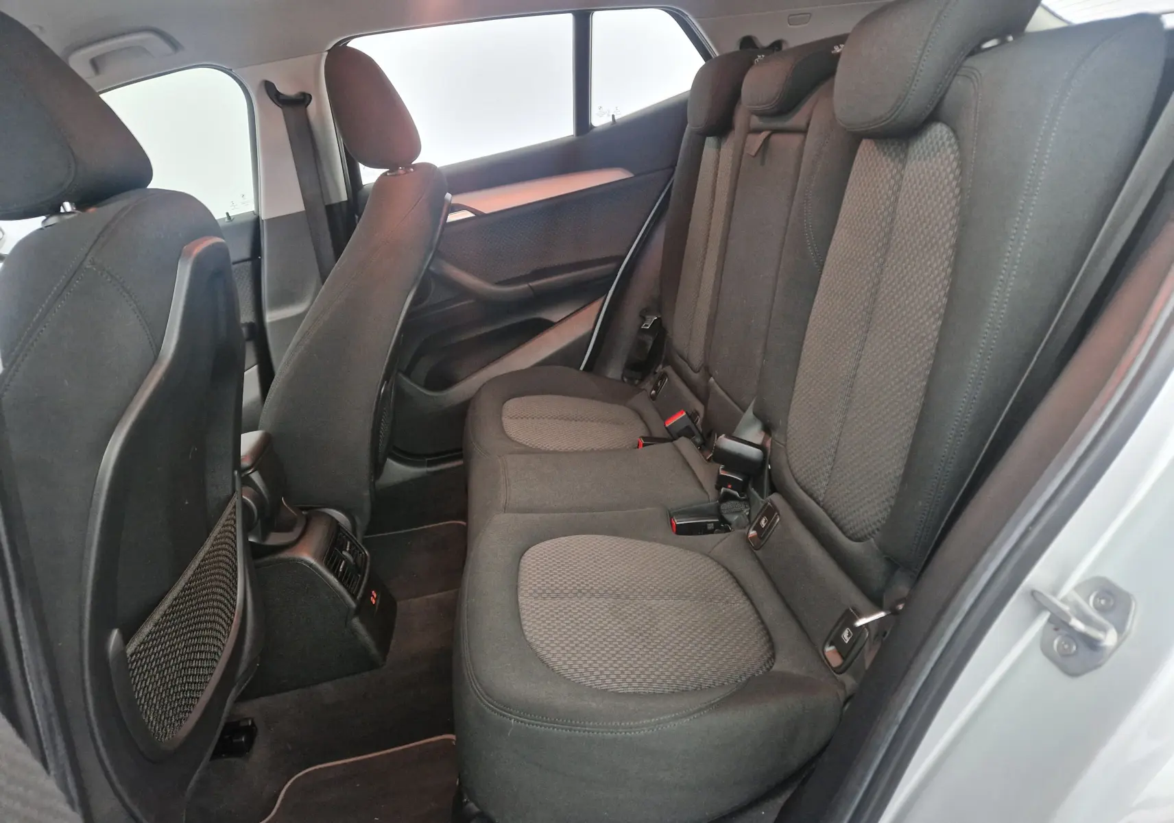 Vue intérieure côté droit des sièges arrière en tissu gris du BMW X2 gris clair métal, montrant l'espace et les appuie-têtes.