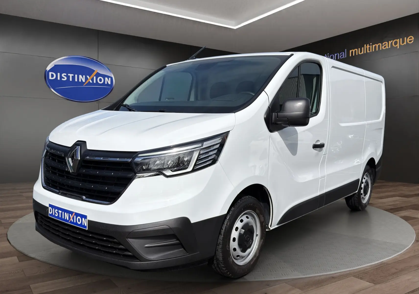 Vue 3/4 avant droite d’un Renault Trafic Fourgon blanc 2024 avec calandre noire et jantes acier simples.