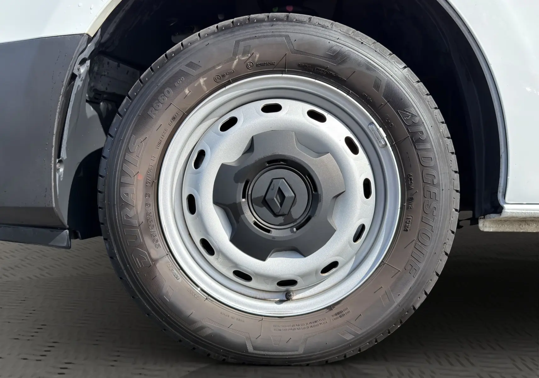 Gros plan sur la roue avant droite blanche d’un Renault Trafic Fourgon 2024 avec jante acier et logo Renault central.