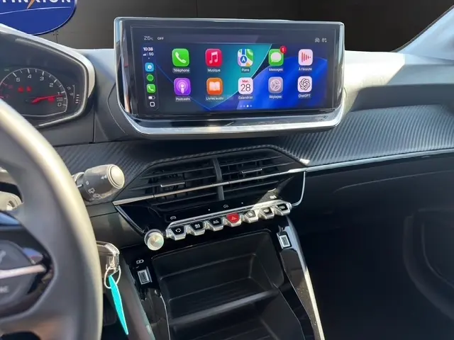 Vue intérieure du tableau de bord de la Peugeot 208 2025 gris clair, avec écran tactile central et commandes piano noires.