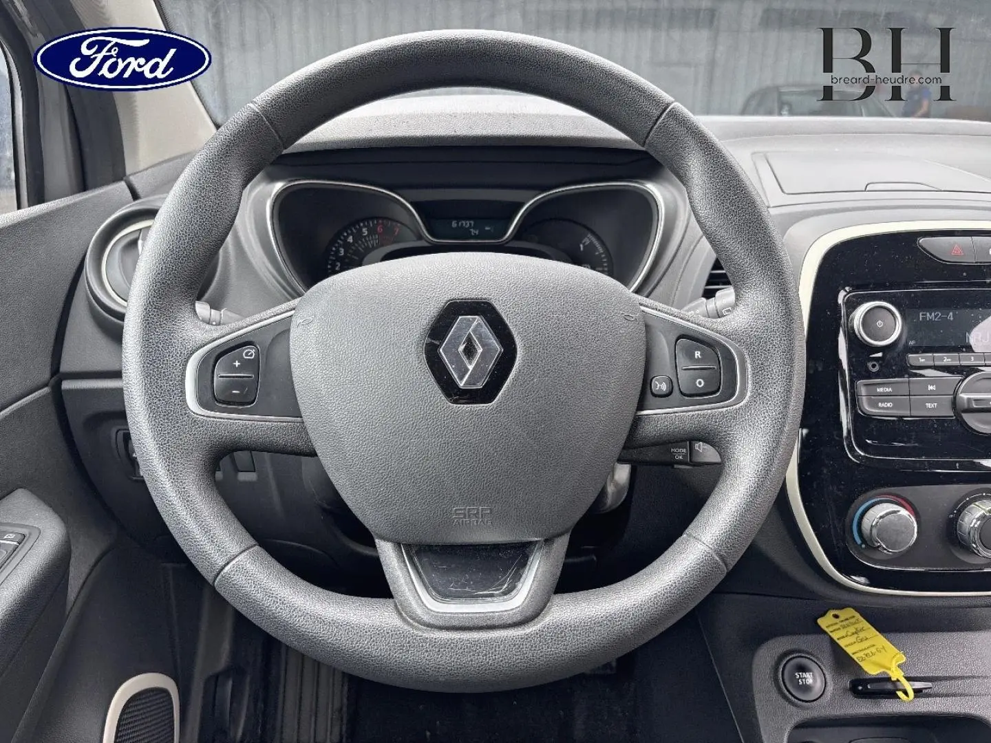 Vue intérieure centrée sur le volant Renault Captur gris avec tableau de bord et commandes visibles.