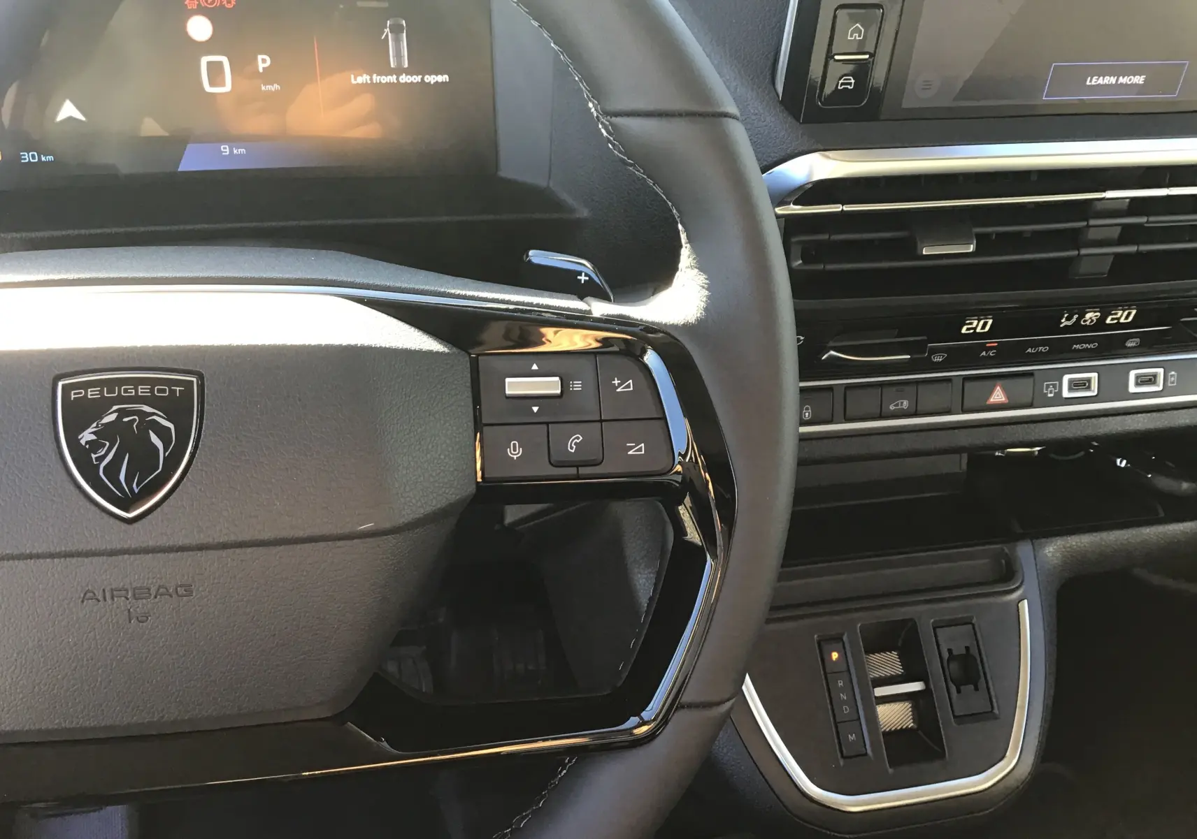 Vue rapprochée du volant et tableau de bord noir du Peugeot Expert Fourgon blanc 2024 avec commandes intégrées et écran digital.