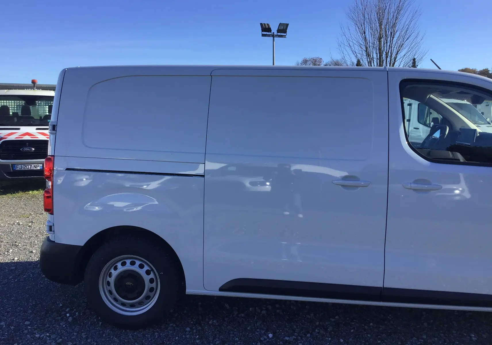 Profil côté droit d'un utilitaire blanc Peugeot Expert Fourgon 2024, avec porte latérale coulissante fermée.