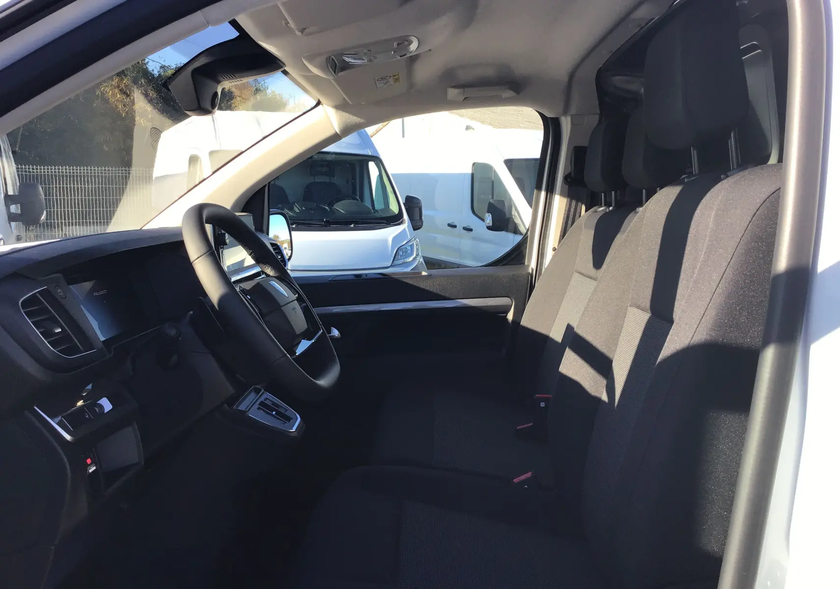 Intérieur du Peugeot Expert Fourgon blanc 2024 vu côté conducteur, montrant le tableau de bord et les sièges noirs.