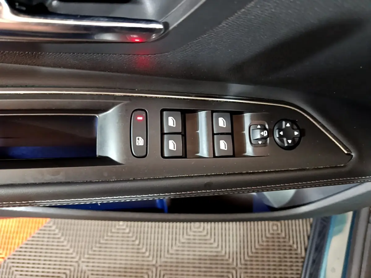 Vue rapprochée des commandes de lève-vitres et réglage des rétroviseurs côté conducteur du Peugeot 5008 bleu.