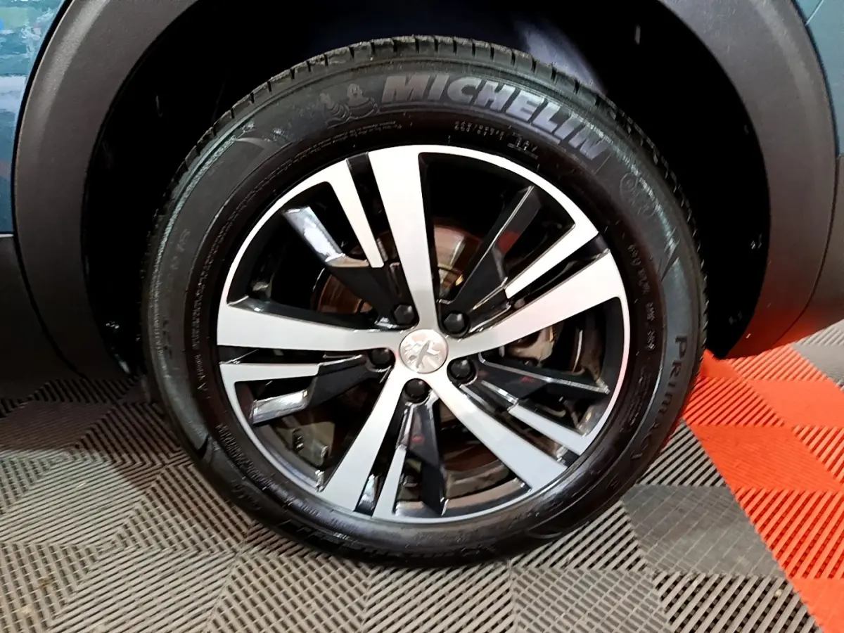 Gros plan sur la jante alliage bicolore et pneu Michelin du côté avant gauche d'un Peugeot 5008 bleu 2018.