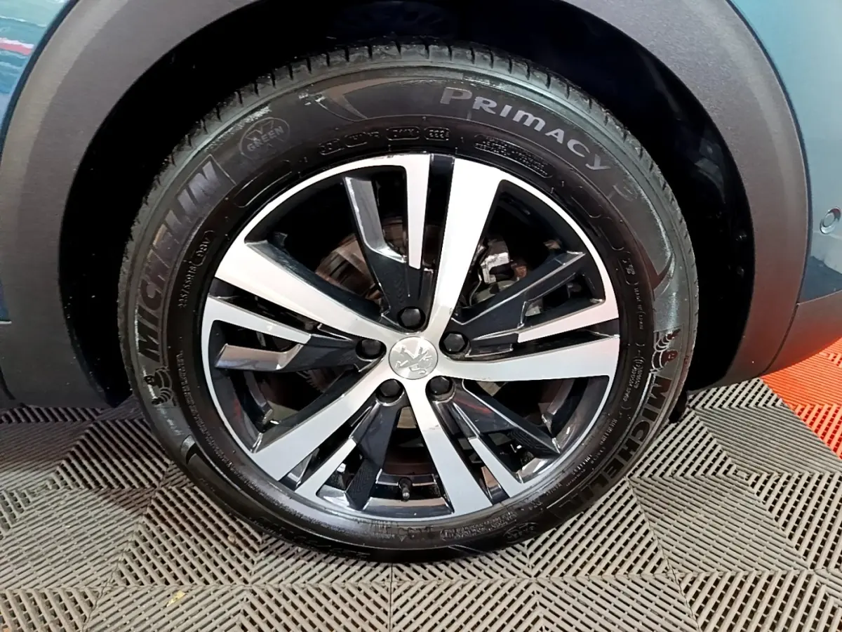 Gros plan sur la roue avant droite du Peugeot 5008 bleu, jante alliage bicolore et pneu Michelin Primacy 3.