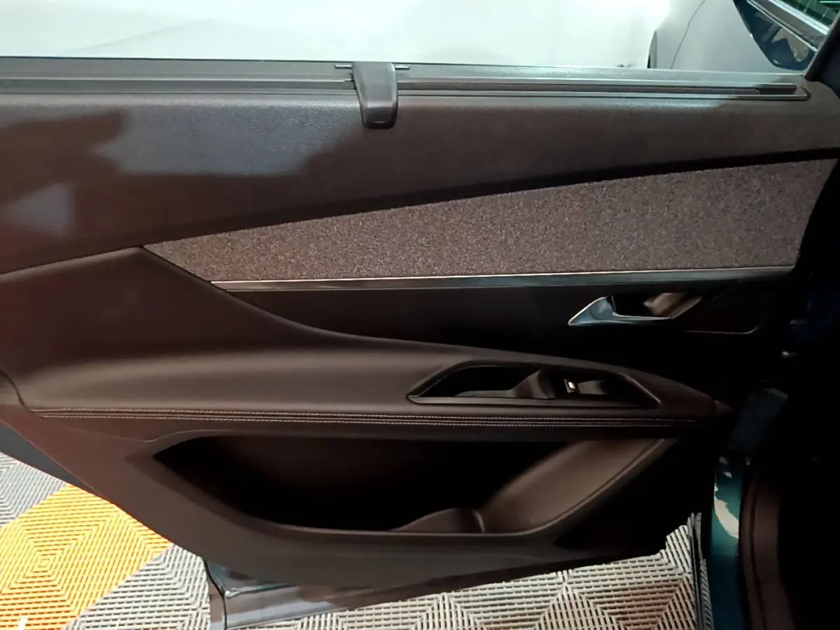 Vue intérieure du panneau de porte côté droit du Peugeot 5008 bleu, avec garniture tissu et commandes électriques.