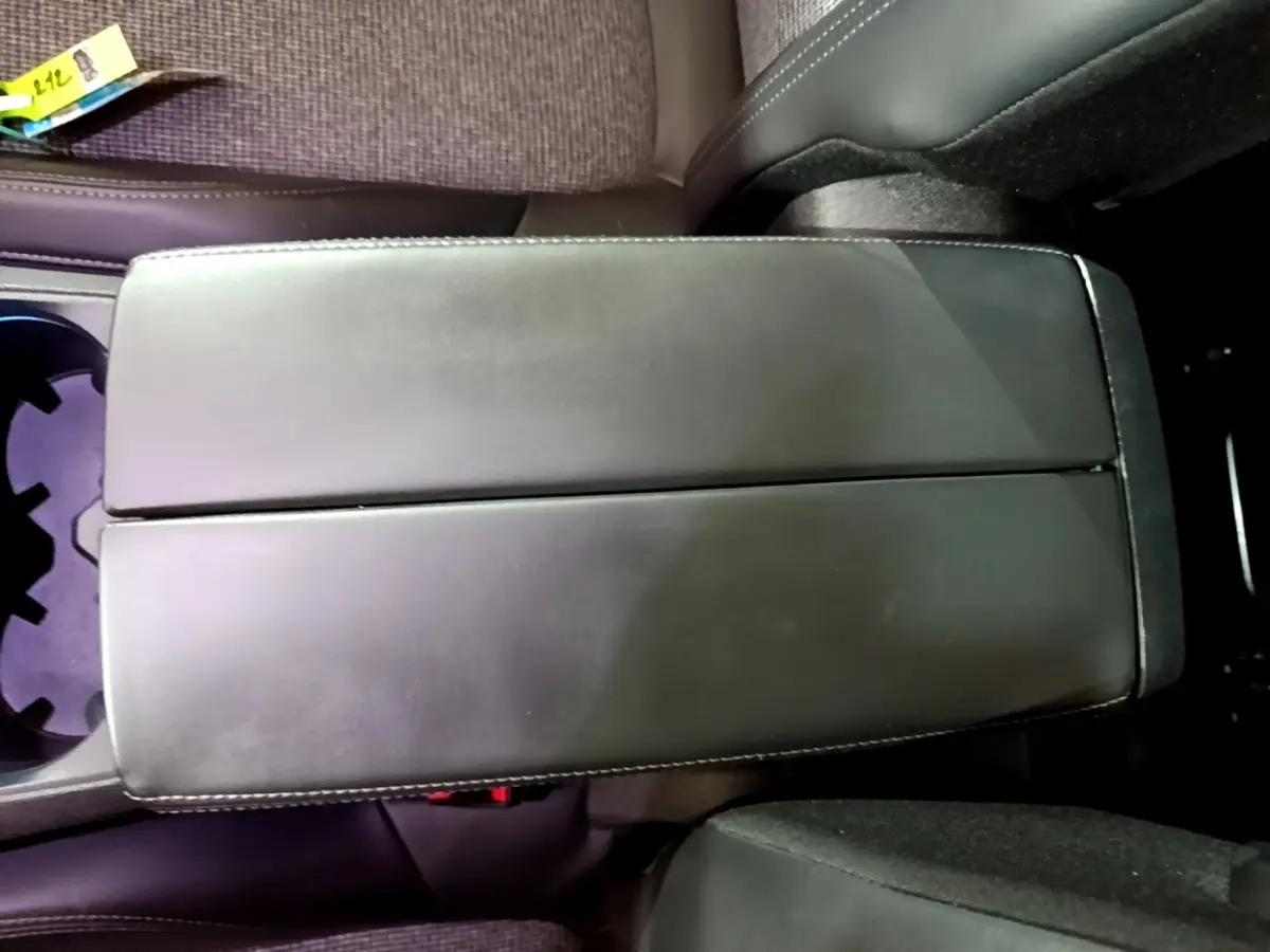 Vue rapprochée de l'accoudoir central noir en cuir entre les sièges avant du Peugeot 5008 bleu 2018.