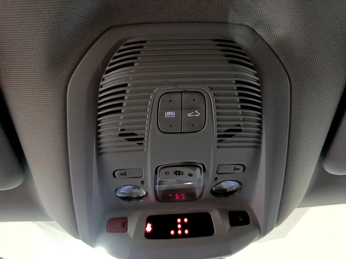 Vue en gros plan du plafonnier intérieur gris du Peugeot 5008 bleu, avec commandes d'éclairage et affichage digital rouge.