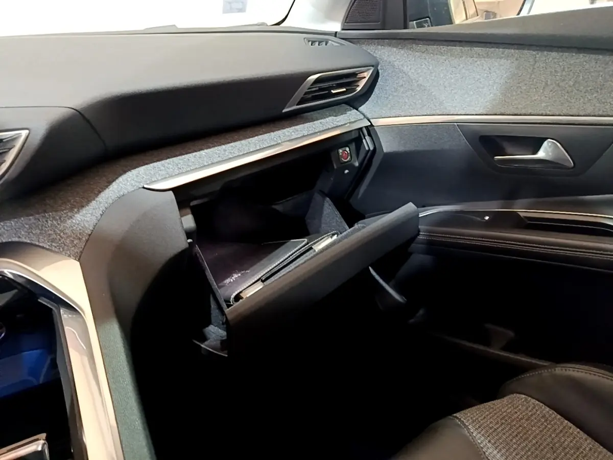 Intérieur côté passager du Peugeot 5008 2018, boîte à gants ouverte, tableau de bord et garnitures noires visibles.