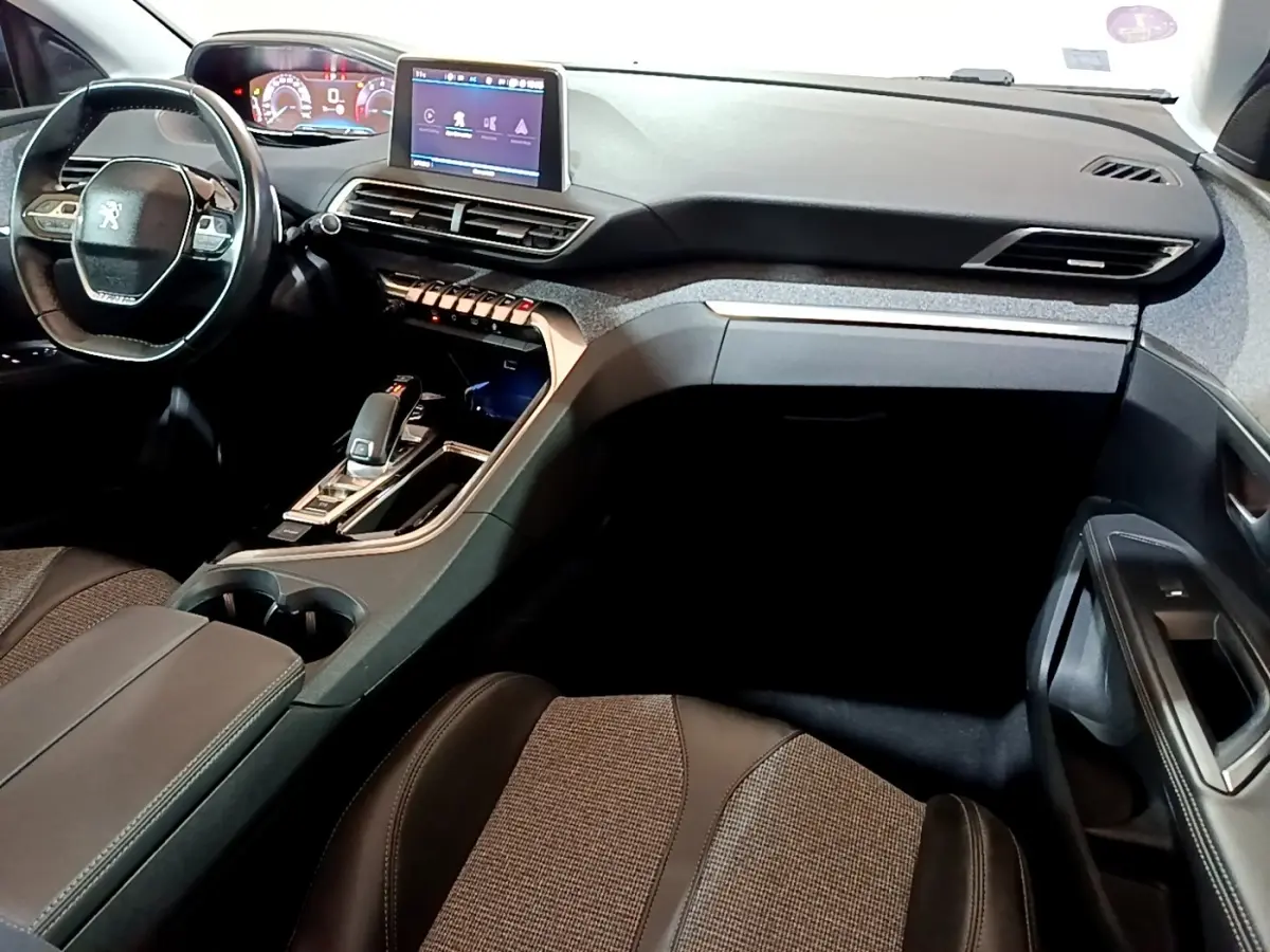Intérieur Peugeot 5008 bleu, vue côté passager sur tableau de bord moderne avec écran tactile et volant cuir.