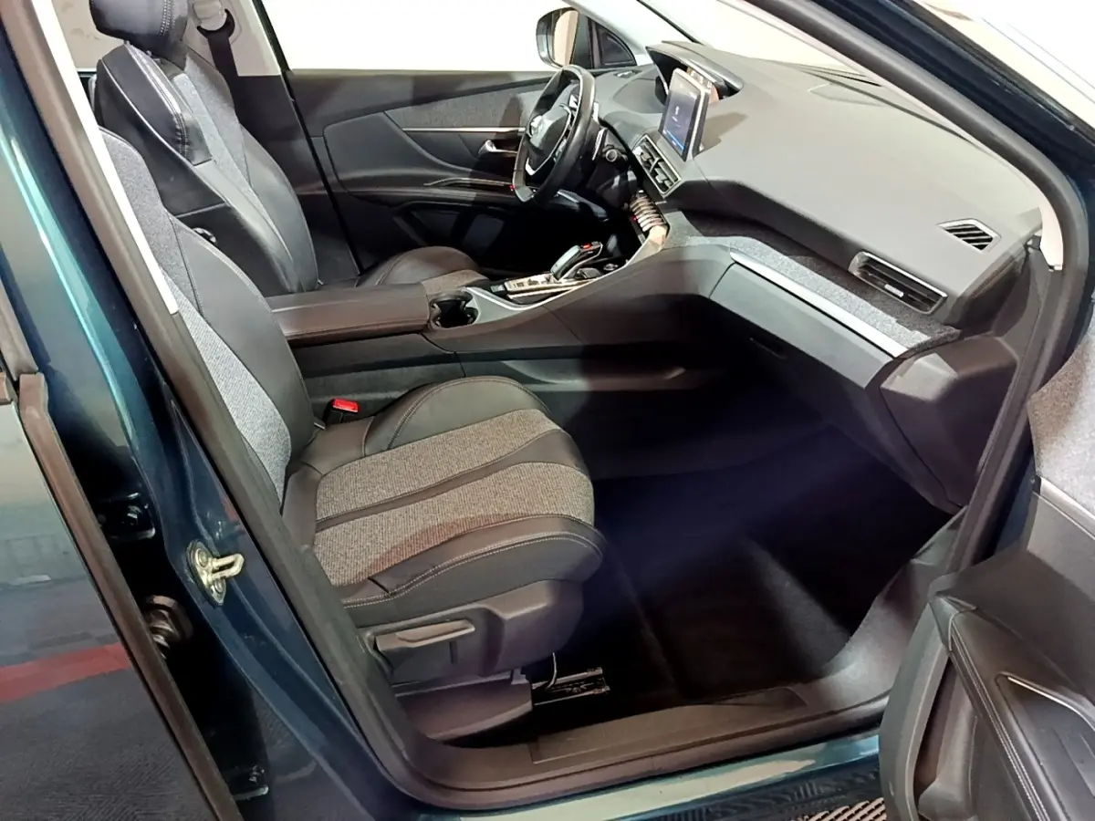 Intérieur côté conducteur du Peugeot 5008 bleu 2018, montrant sièges bi-matière et tableau de bord avec écran tactile.