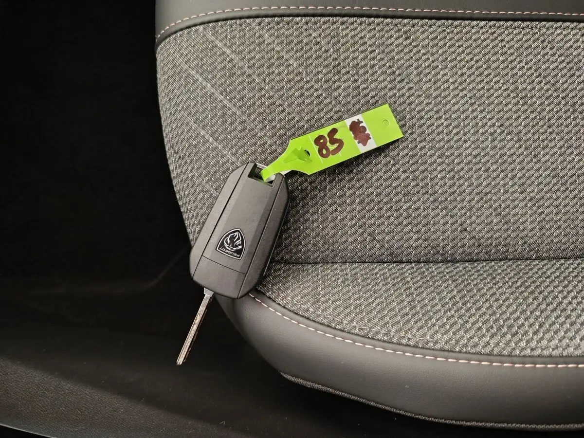 Clé de voiture Peugeot posée sur un siège tissu gris avec surpiqûres, intérieur d'une Peugeot 208 PureTech 100 S&S Allure 2025.