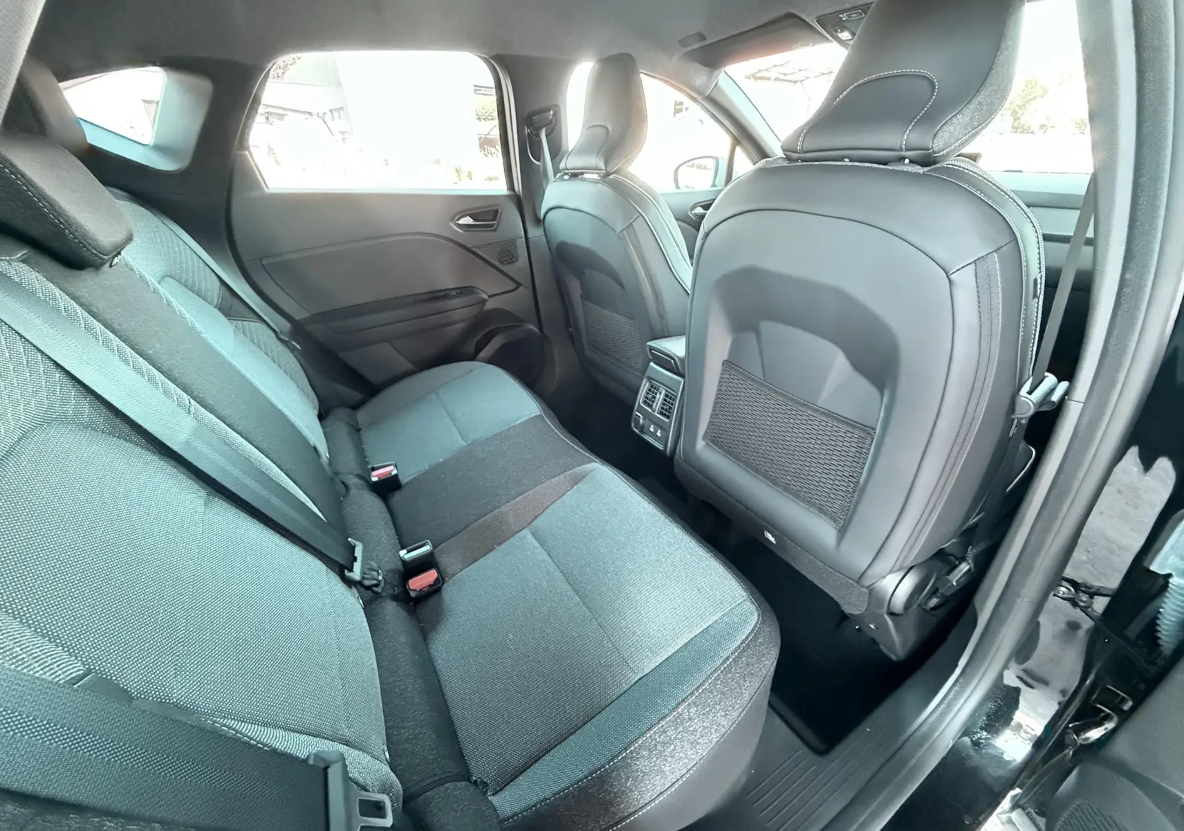 Vue intérieure arrière côté droit du Renault Captur 2025 noir, sièges tissu gris et noir avec appuie-têtes intégrés.