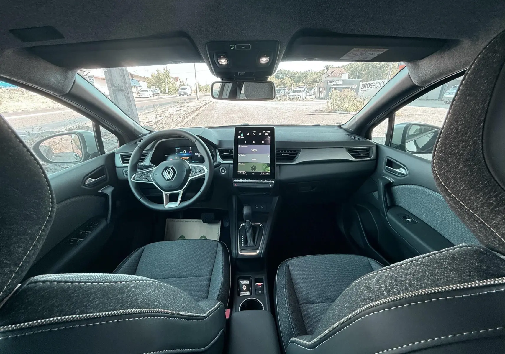 Vue intérieure avant du Renault Captur noir 2025, montrant tableau de bord moderne et écran tactile vertical.