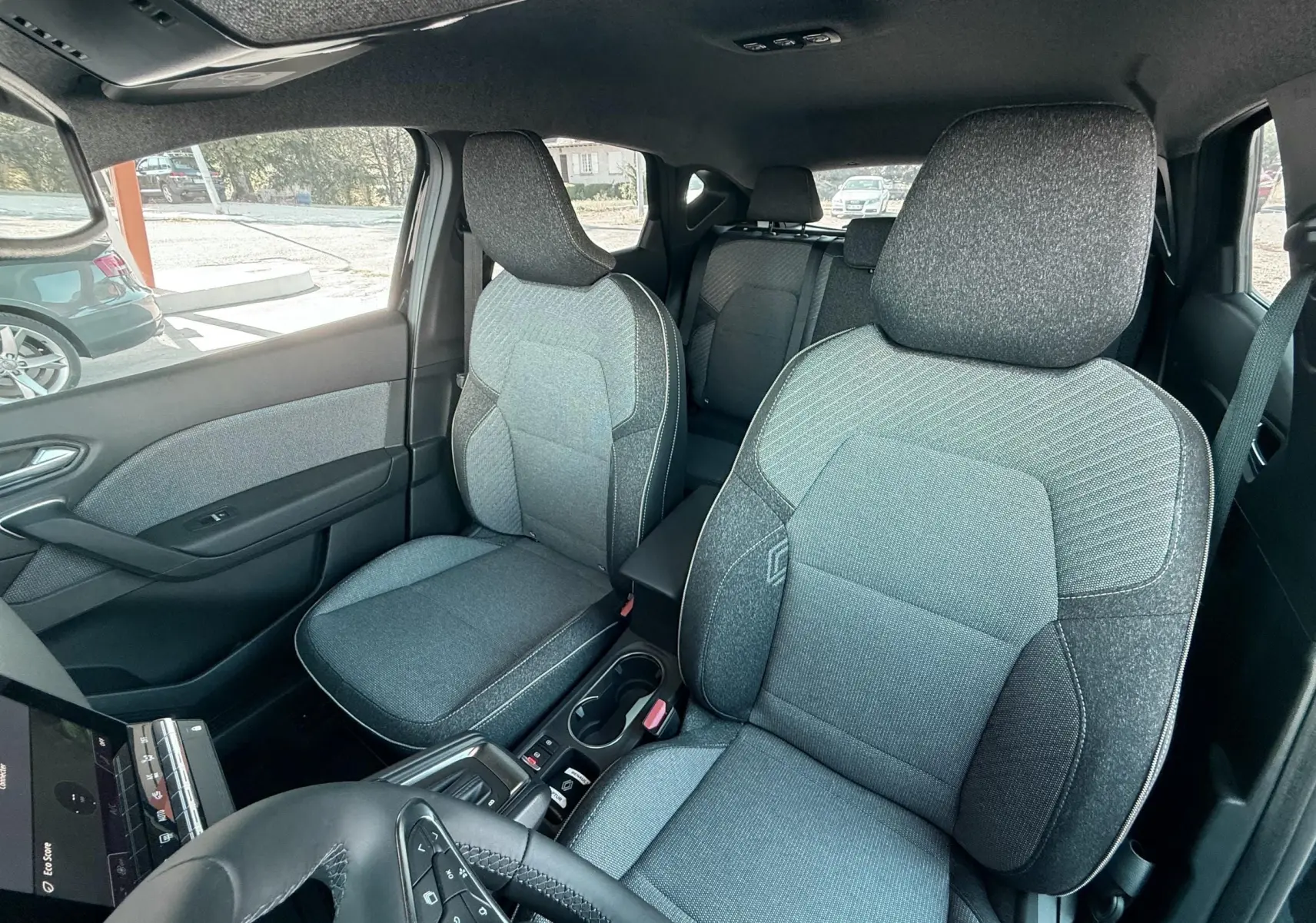 Vue intérieure avant du Renault Captur 2025 noir, montrant les sièges tissu gris et noir avec détails contrastants.