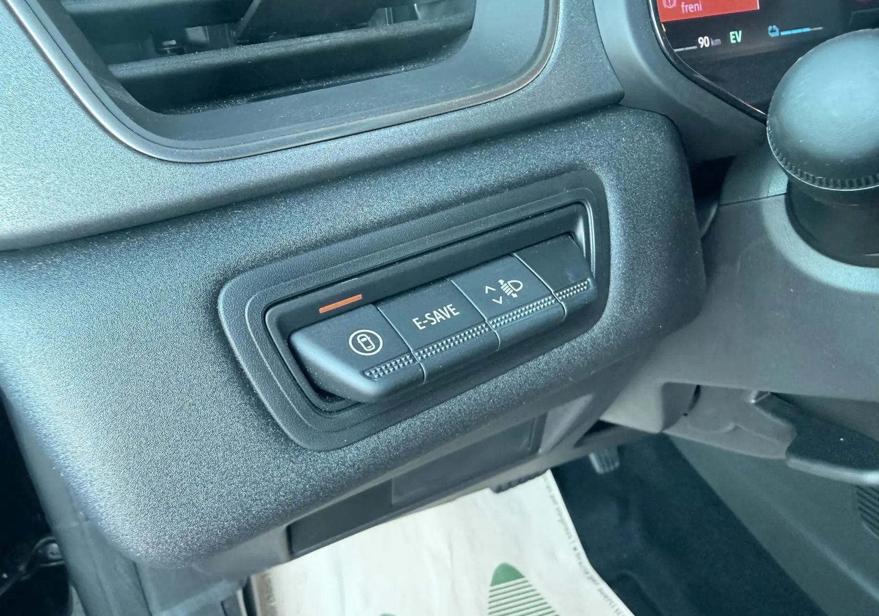 Gros plan sur les commandes E-SAVE et réglage des phares du tableau de bord du Renault Captur noir 2025.