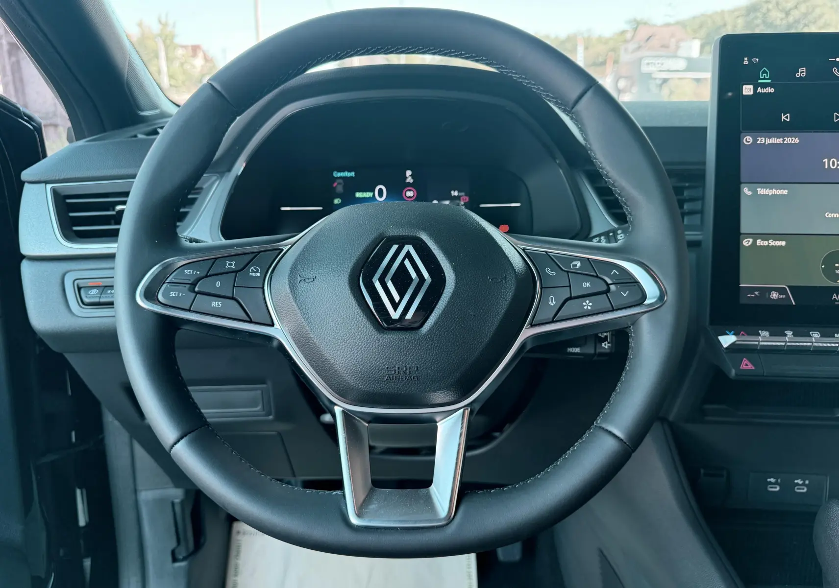 Vue intérieure centrée sur le volant noir de la Renault Captur 2025 avec tableau de bord et écran tactile visible à droite.