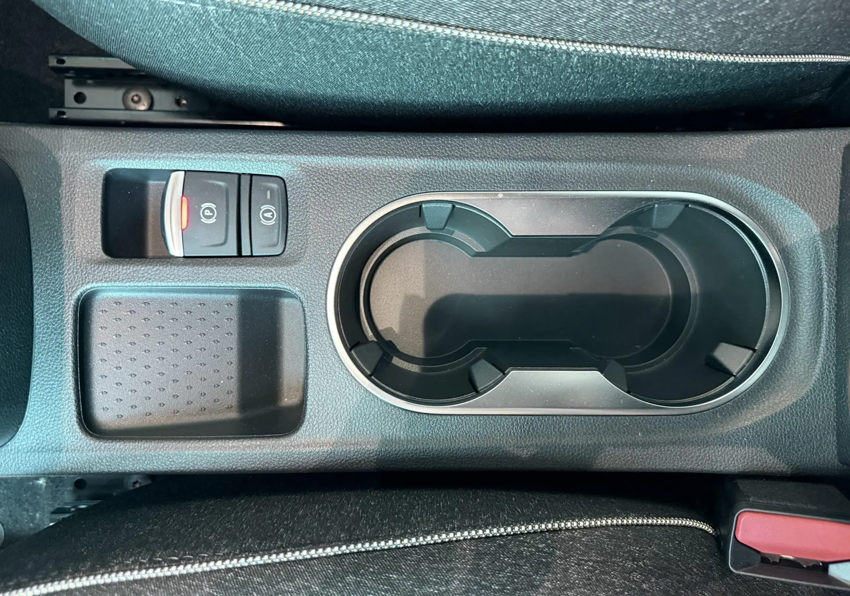 Vue rapprochée de la console centrale avec porte-gobelets et boutons de frein à main sur Renault Captur noir 2025.