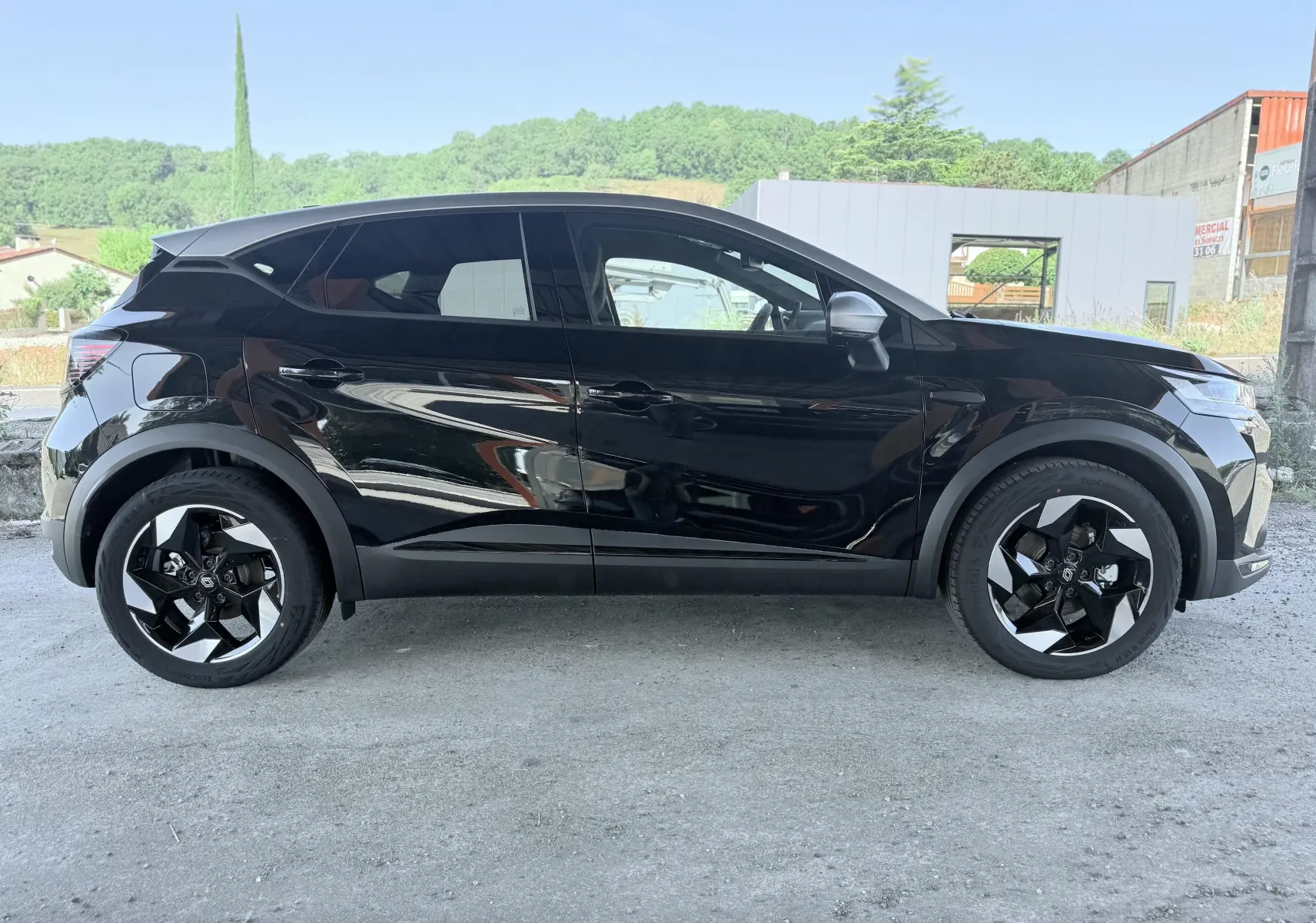 Profil latéral gauche du Renault Captur noir 2025 avec jantes bi-ton et lignes sculptées distinctives.