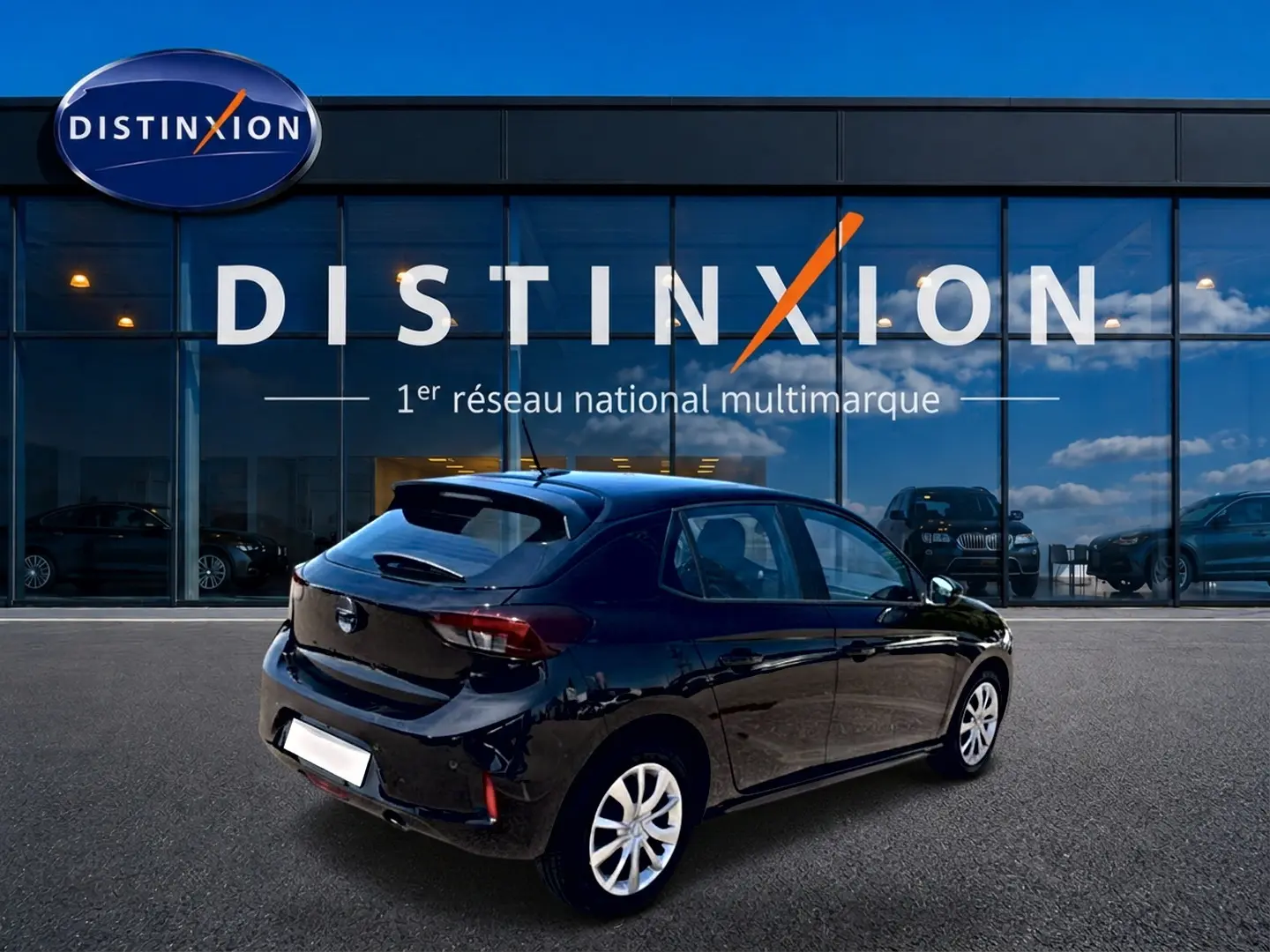Opel Corsa 1.2 turbo 100 edition noire vue 3/4 arrière droit, avec becquet et jantes argentées devant showroom Distinxion.