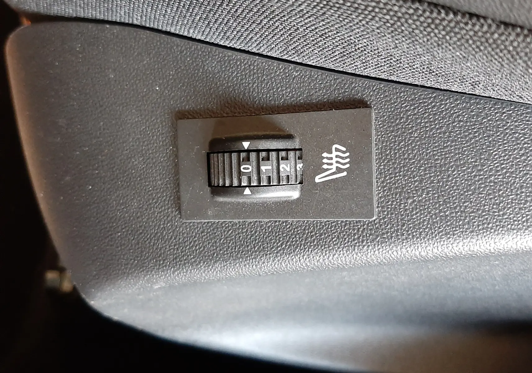 Gros plan sur le réglage de chauffage de siège noir dans l'habitacle d'une Peugeot 2008 GT Line rouge Ultimate Metal 2019.