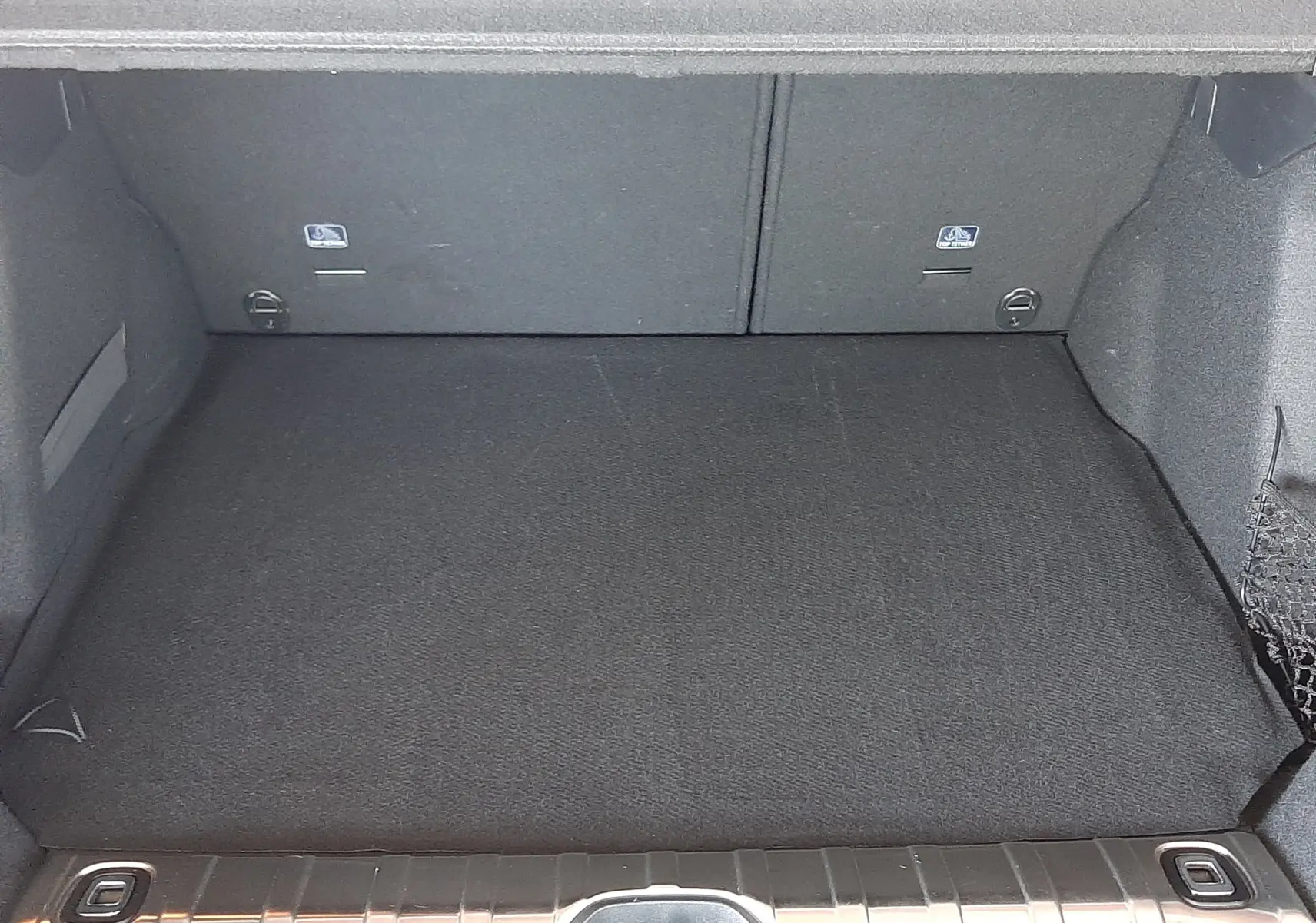 Coffre ouvert vu de l'arrière d'un Peugeot 2008 rouge Ultimate Metal, espace de chargement propre et vide.