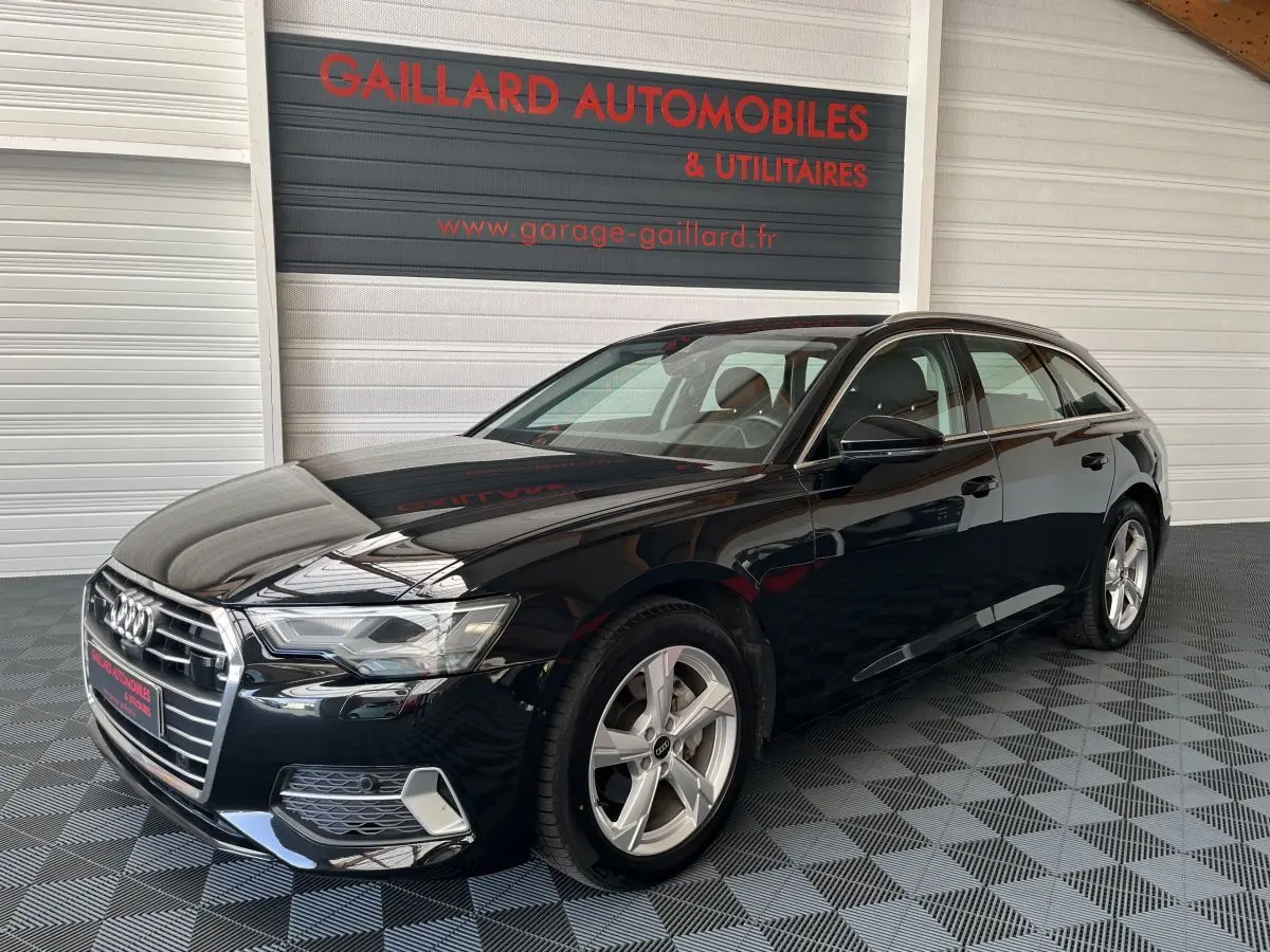 Audi A6 40 TDI S Tronic hybride noire vue 3/4 avant droit dans un showroom avec sol damier gris.