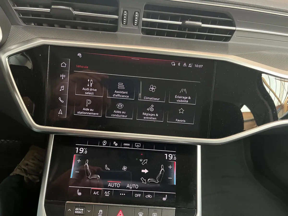 Écran tactile central et commandes de climatisation dans l'habitacle noir d'une Audi A6 40 TDI S Tronic hybrid 2022.