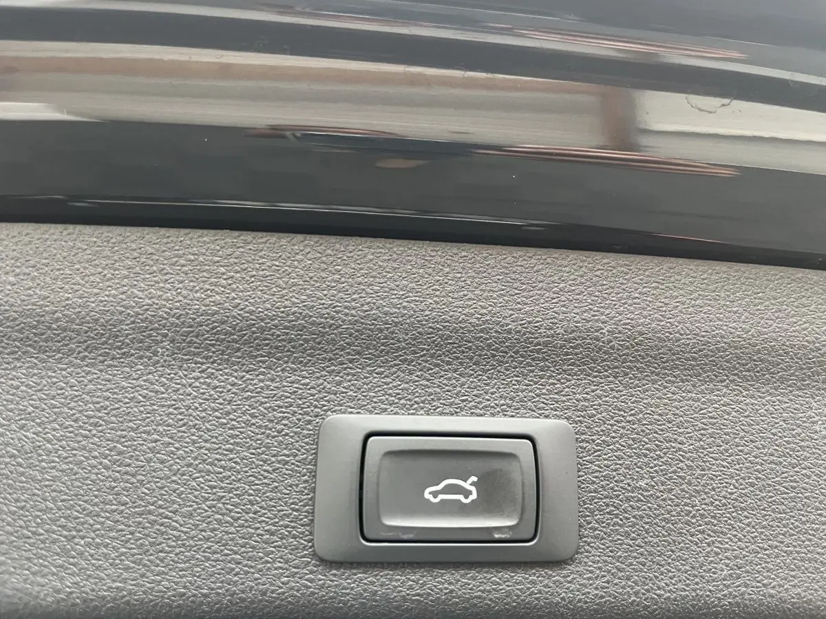 Bouton d'ouverture électrique du coffre sur la garniture intérieure noire d'une Audi A6 40 TDI S Tronic hybrid 2022.
